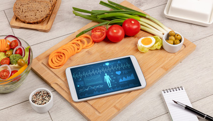 Healthy food composition with tablet. Body diagnosis on the screen