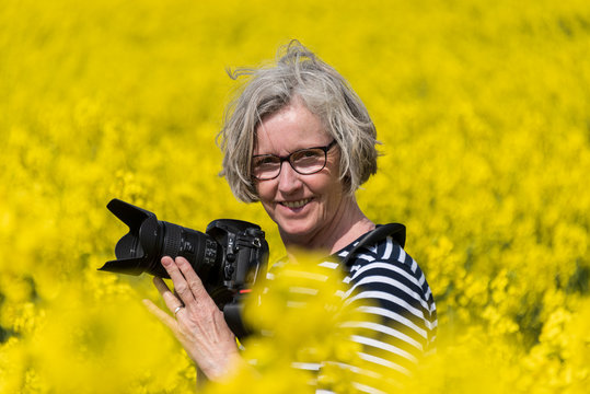 Fotografin mitten in einem Rapsfeld in voller Bl&uuml;te im Fr&uuml;hjahr