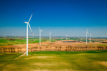 Flying above big wind turbines in a field