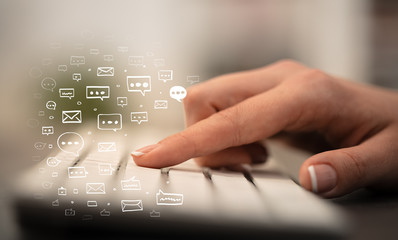 Business woman hand typing on keyboard with chat icons around