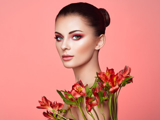 Portrait of beautiful young woman with Alstroemeria flowers. Brunette woman with luxury makeup....