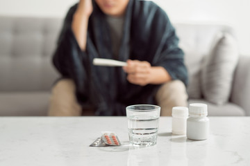 Sick man lying on sofa checking his temperature at home in the living room