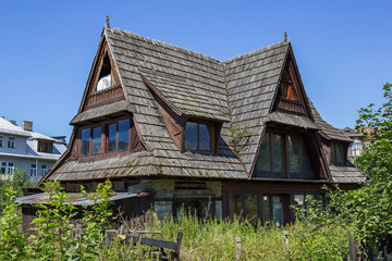 An abandoned traditional wooden house named Staszelowka, surrounded by modern houses in Zakopane region, Poland