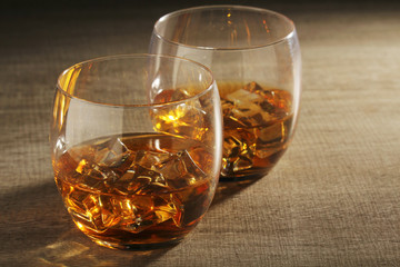 Two glasses with whiskey with ice cubes