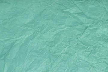 Texture of crumpled turquoise, wrapping paper, closeup. Green old background
