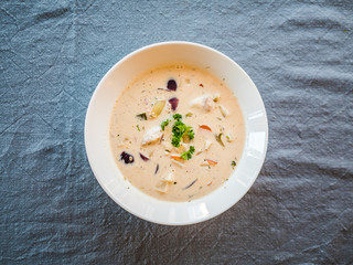 Norwegian Fish Soup with cod and salmon in a white plate, top view from above.