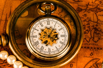 Fototapeta na wymiar Antique clock in the background of a magnifying glass and books. Vintage style. 1565 old map of the year.
