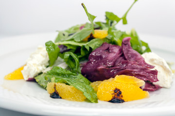 salad of greek feta cheese, oranges and lettuce on a white background in a plate