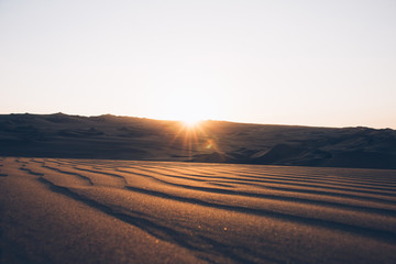 Fototapeta na wymiar Beautiful sand dunes ripples in the desert, warm dry sand at sunset. Nature landscape. Huacachina desert, Ica Region, Peru. Toned image.
