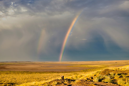 Spectacular landscape with a colorful rainbow in stormy sky, yellow dry grass and bright blue sky. Location on the border between Mongolia and China in the Gobi Desert. China nature landscape. © eskstock