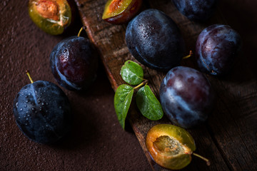 Plums in drops on a dark wood background. Toning. Selective focus.