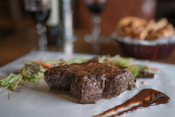 Sirloin steak on cutting board and paper. Eating and leisure concept. Roasted beef. Delicious hot beef steak. Grilled beef steaks with vegetables. Organic healthy food. Toned image. Selective focus.