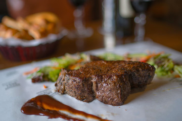 Sirloin steak on cutting board and paper. Eating and leisure concept. Roasted beef. Delicious hot beef steak. Grilled beef steaks with vegetables. Organic healthy food. Toned image. Selective focus.