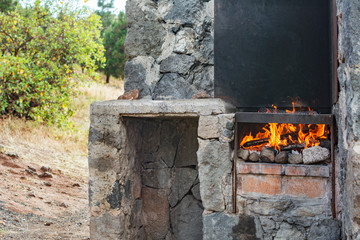 Barbecue day outdoors, in nature. Stone construction with grill and fire.