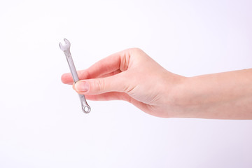 A wrench in the hand of a girl. Symbol of hard work, feminism and labor day. Isolate on white background.