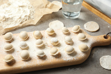 Fototapeta na wymiar Board with raw dumplings on table. Process of cooking