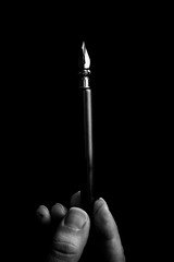 female hand elegantly holding an ink pen with a metal tip close-up on a black background. classic fountain pen isolated macro black and white. copy space. vertical