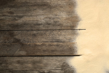 Beach sand on wooden background, top view with space for text