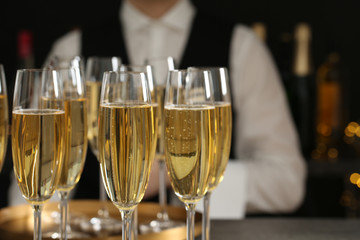 Glasses of champagne and waiter in restaurant, closeup. Space for text