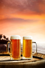 Cold fresh beer on barrel of wood. Summer sunset time. Sea landscape with beach and palms. Free space for your bottle. 