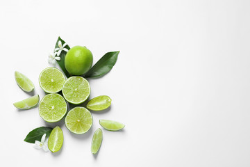 Limes, flowers and leaves on white background, top view. Citrus fruits