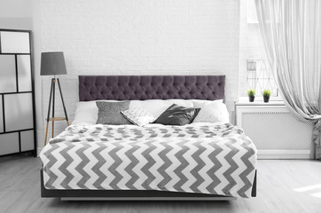 Bed with pillows and plaid in modern room interior