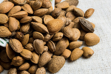Obraz premium Almond nut in shell heap on beige fabric texture