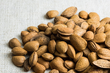 Almond nut in shell heap on beige fabric texture