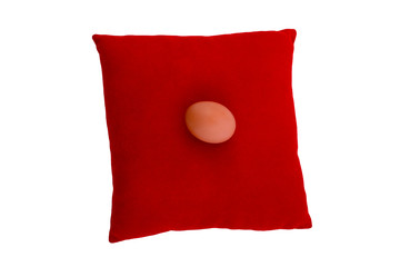 Chicken egg on red velvet cushion isolated on white background