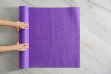 Woman rolling yoga mat on floor, top view. Space for text