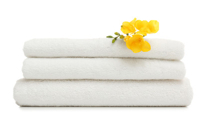 Stack of clean folded towels with flowers on white background