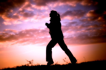 Running woman - jogger woman - in nature over sunset sky like sport, hobby and fitness concept 