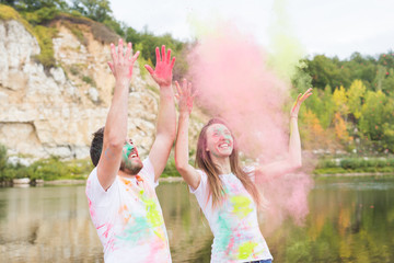 Obraz premium Festival holi, holidays, tourism and nature concept - Portrait of woman and man covered multi-colored dust