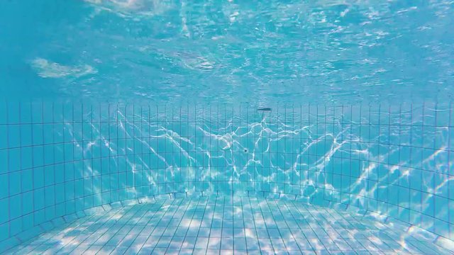 Wave texture on the bottom of swimming pool and sun rays