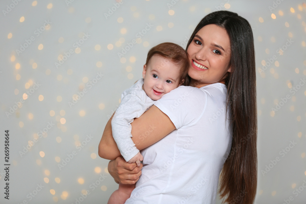 Poster Portrait of young mother and her adorable baby against defocused lights