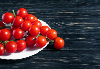 Fototapeta na wymiar Cherry tomatoes in the white plate on the wooden table