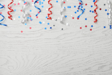 Fototapeta premium Flat lay composition with colorful party streamers on wooden table, space for text. USA Independence Day