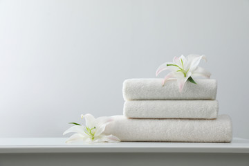 Naklejka na ściany i meble Stack of fresh towels with flowers on table against white background. Space for text