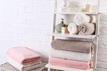 Shelving unit with clean towels and toiletries near brick wall