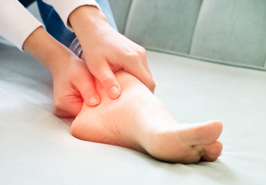 A young woman massaging her painful ankle