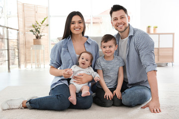 Happy couple with children sitting on floor at home. Family weekend