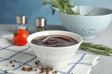 Bowl with tasty barbecue sauce on table