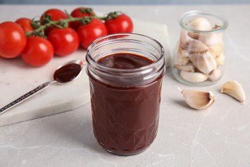 Composition with jar of barbecue sauce on light table