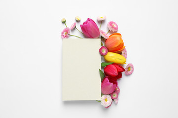 Beautiful composition with spring flowers and blank card on white background, top view. Space for text