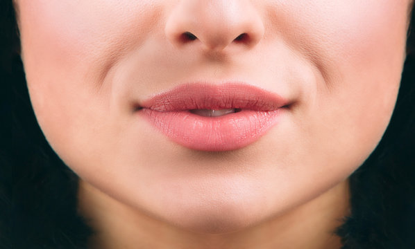 Close up of nice young woman's lips smiling a bit. Short black hair. Healthy skin. Cut view.