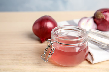 Glass jar with onion syrup and fresh ingredient on wooden table. Space for text