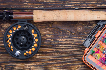 fishing rod and reel with an orange fishing line near the bait for fishing on a wooden background