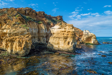 Fototapeta na wymiar Eroding rocks at ocean coastline on bright sunny day