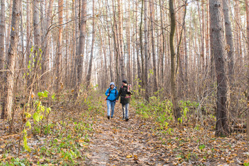 Fototapeta premium adventure, travel, tourism, hike and people concept - smiling couple walking with backpacks over autumn natural background