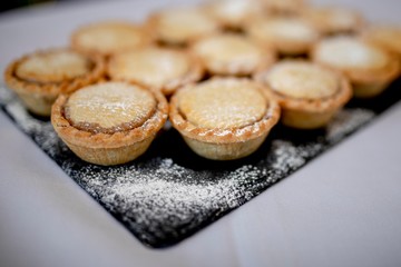 Close up delicious home baked seasonal frosted Christmas mince pies on slate plate on a buffet in a luxury hotel